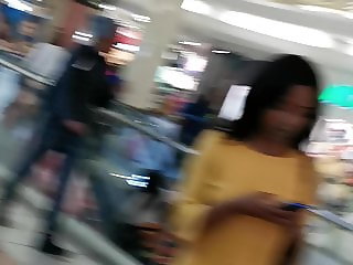 Ebony with shorts under yellow skirt walking up escalators